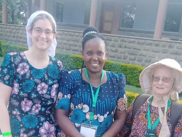 3 women smile at the camera. I’m in a white head scarf and a short sleeved dress with pink and teal flowers. Pastor Pamela is in a two-piece outfit of navy blue with teal and gold circles. Marian Baker has her usual bonnet and wears a dress with large orange flowers on a mottled red background. /images/2023/friends_in_kenyan_dresses.jpg