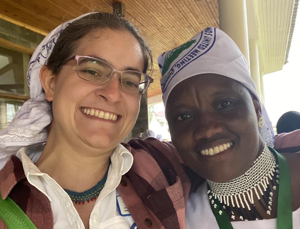Two women smile in a selfie with arms around each other. We both wear white head scarves emblazoned with the Society of Friends Women, and we both wear necklaces beaded in the Samburu style.  /images/2023/maco_rosina.jpg